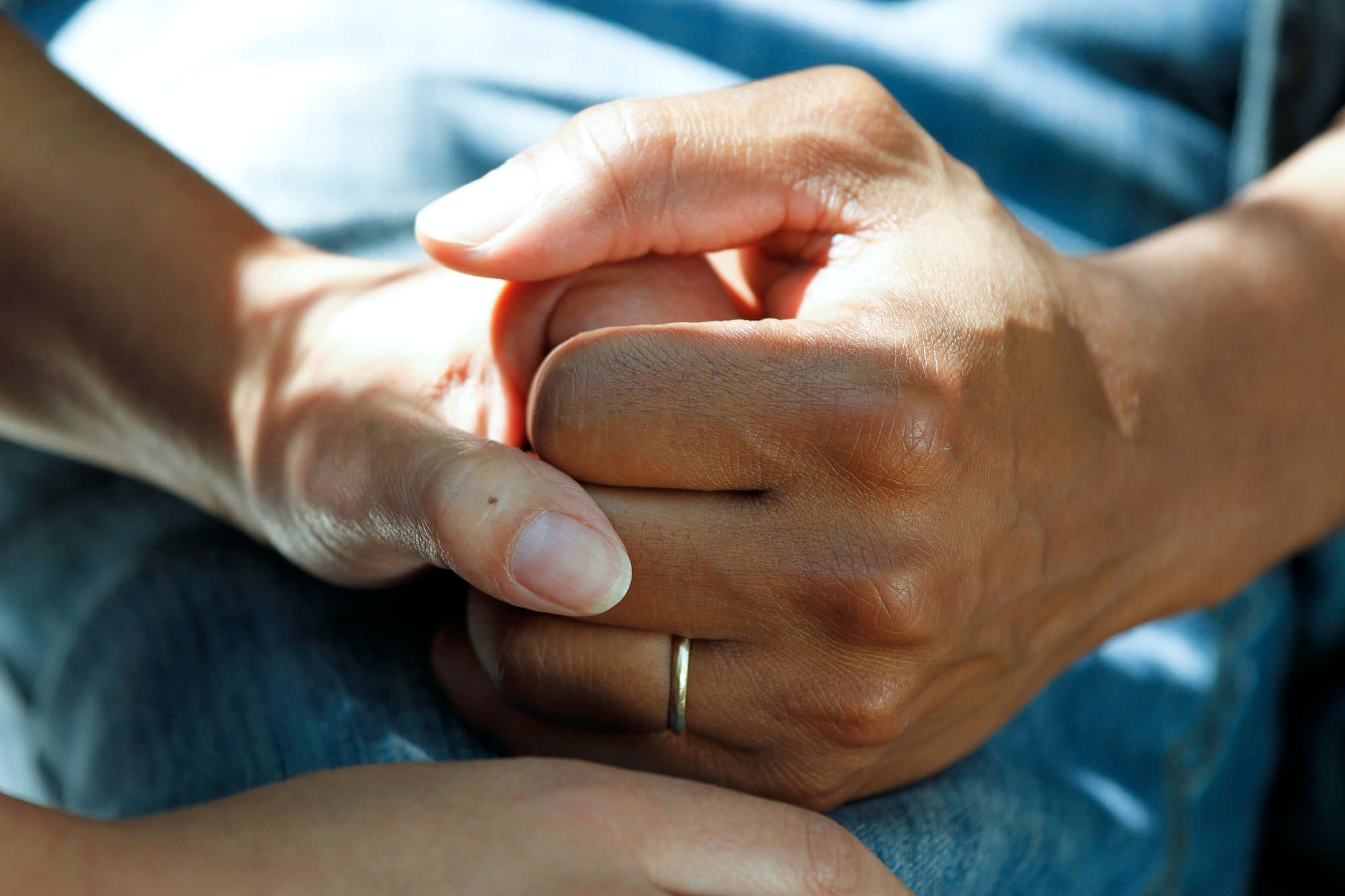 A caregiver's hands resting over an older person's hands